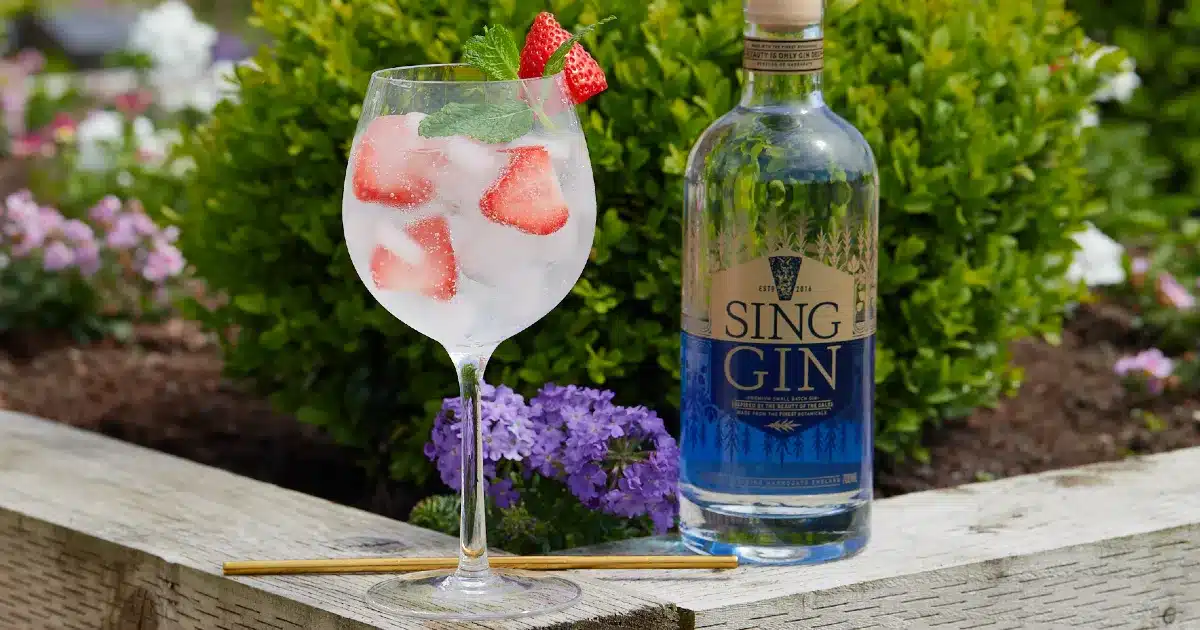 Sing Gin bottle with gin and tonic with a strawberry garnish