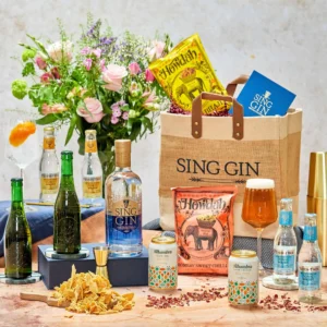 A bottle of gin, beers and food snacks on a table